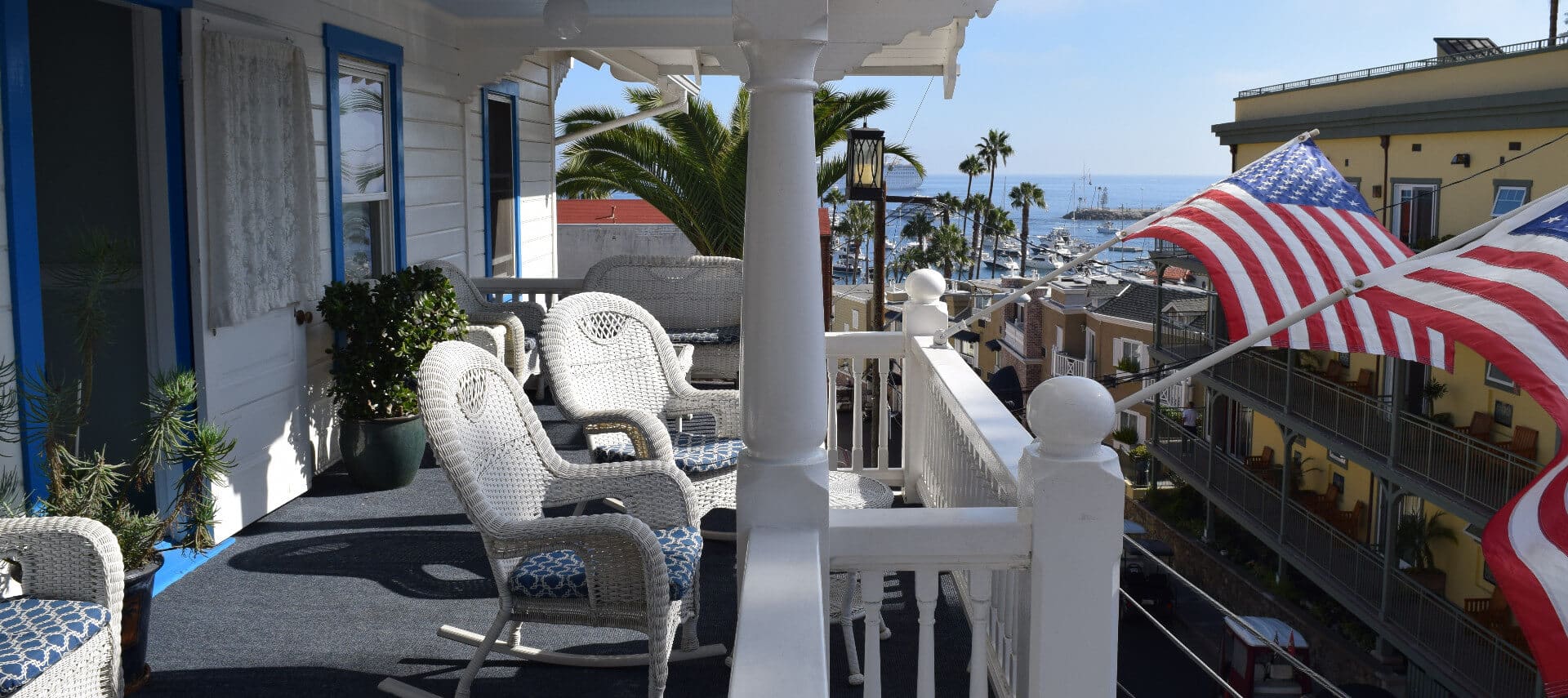Second floor balcony with wicker rocking chairs an American flags overlooking ocean view.