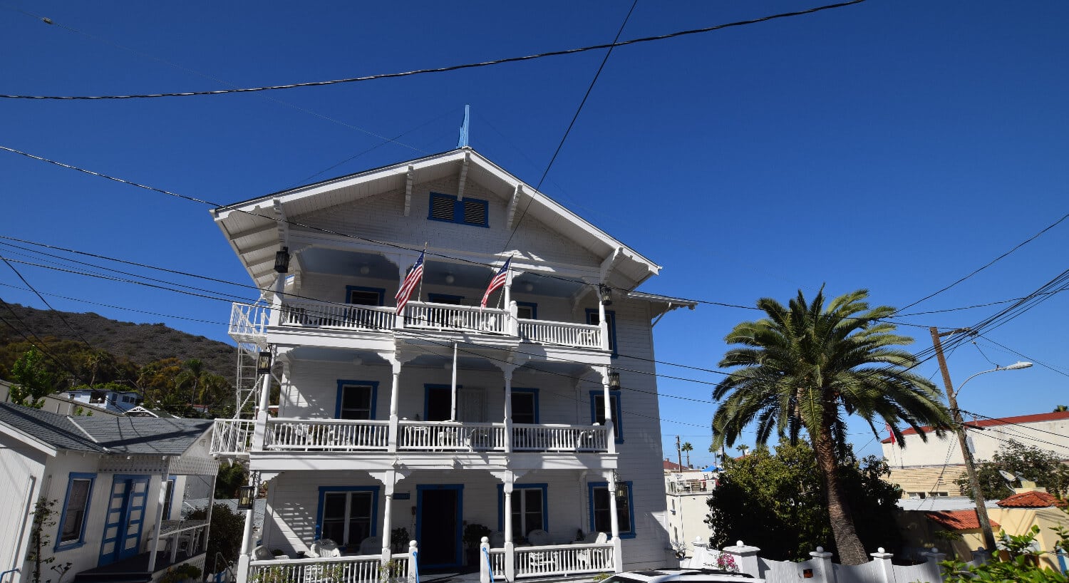 Large white building with multi-story balconies backed by deep blue sky. 