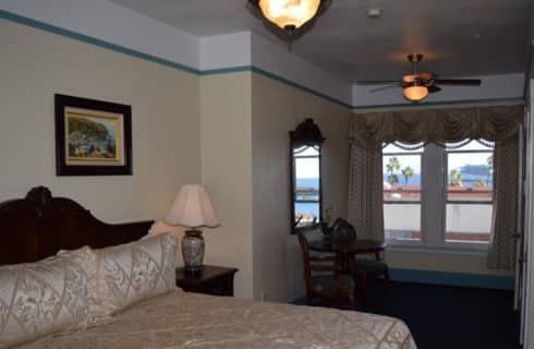 Bedroomw ith a king bed and sitting area painted yellow with blue trim.