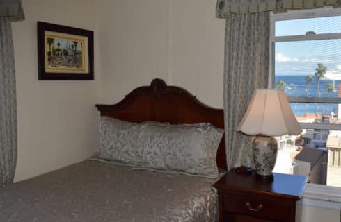 Queen bed in next to window with wooden headboard and nightstand