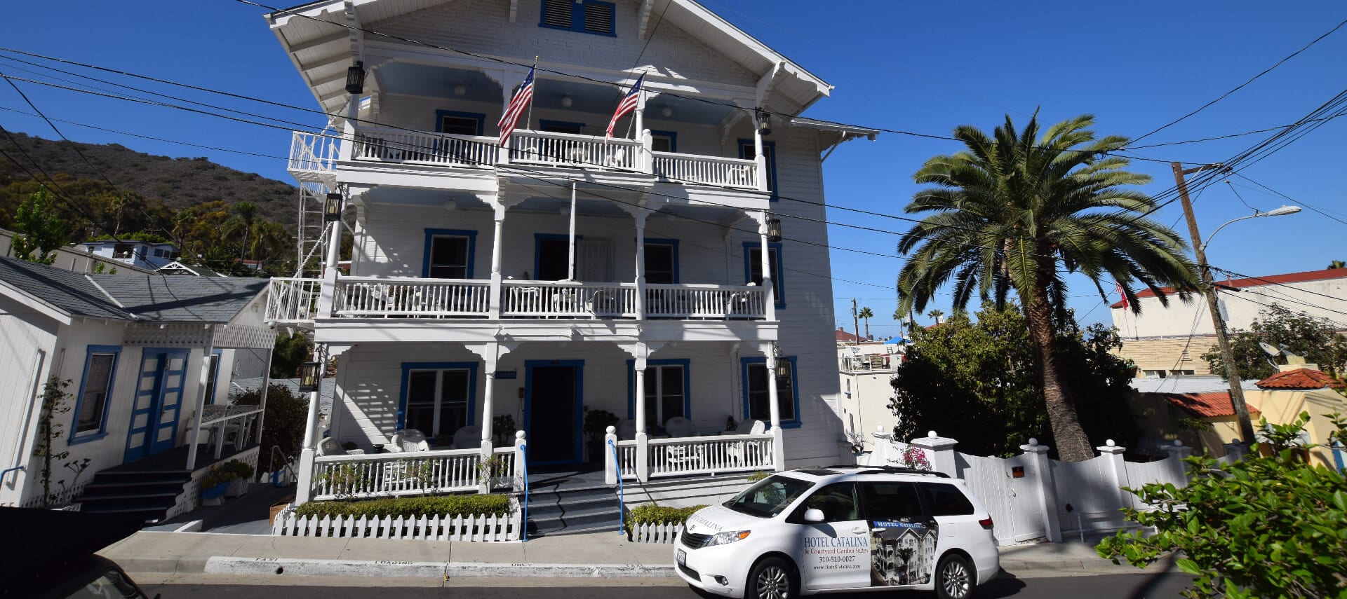 Large white building with multi-story balconies backed by deep blue sky.